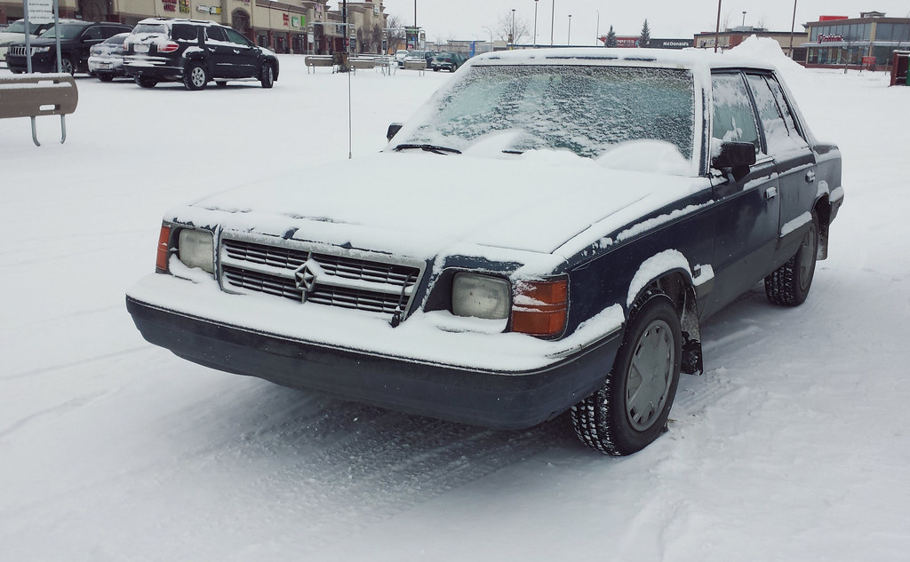 Black car covered with snow in a parking lot