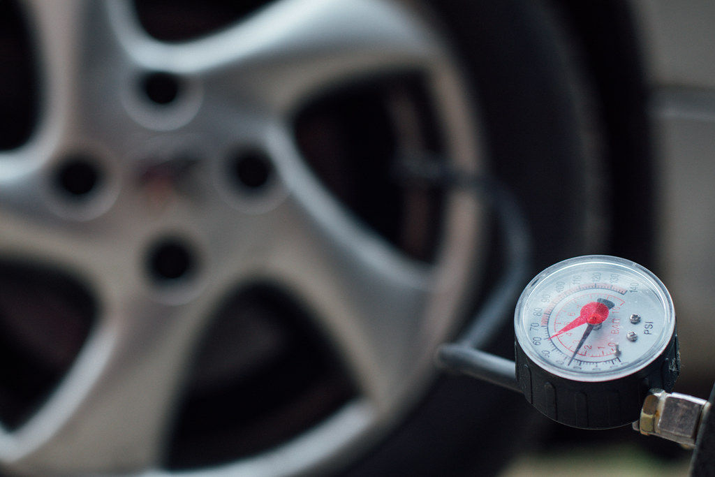 Tire pressure gauge beside a car wheel during maintenance