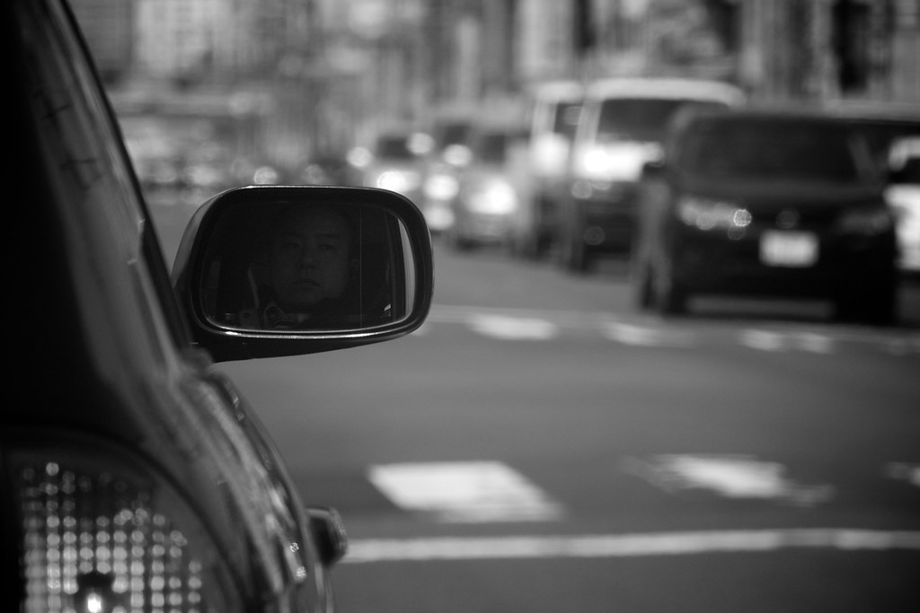 Car side mirror showing traffic on the road behind the vehicle