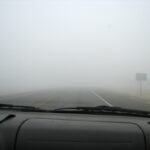 Foggy road seen through a car windshield with faint lane markings