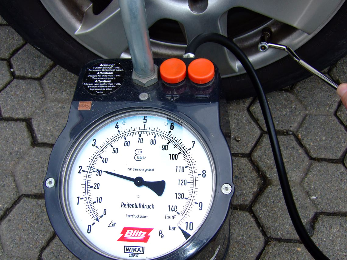 Large tire pressure gauge connected to a car tire valve