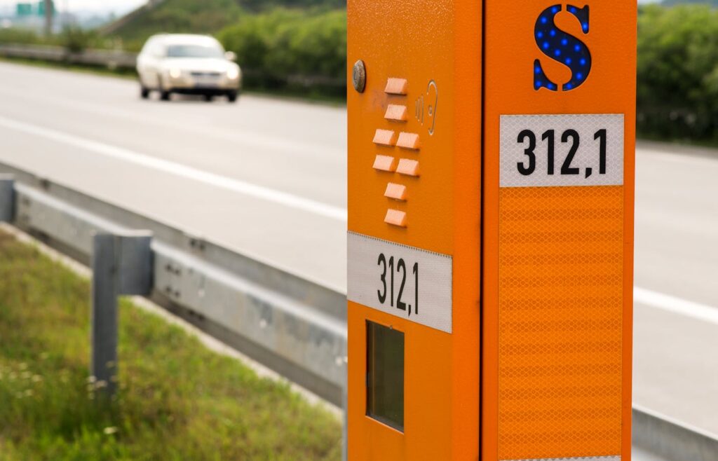 Orange emergency phone box beside highway guardrail