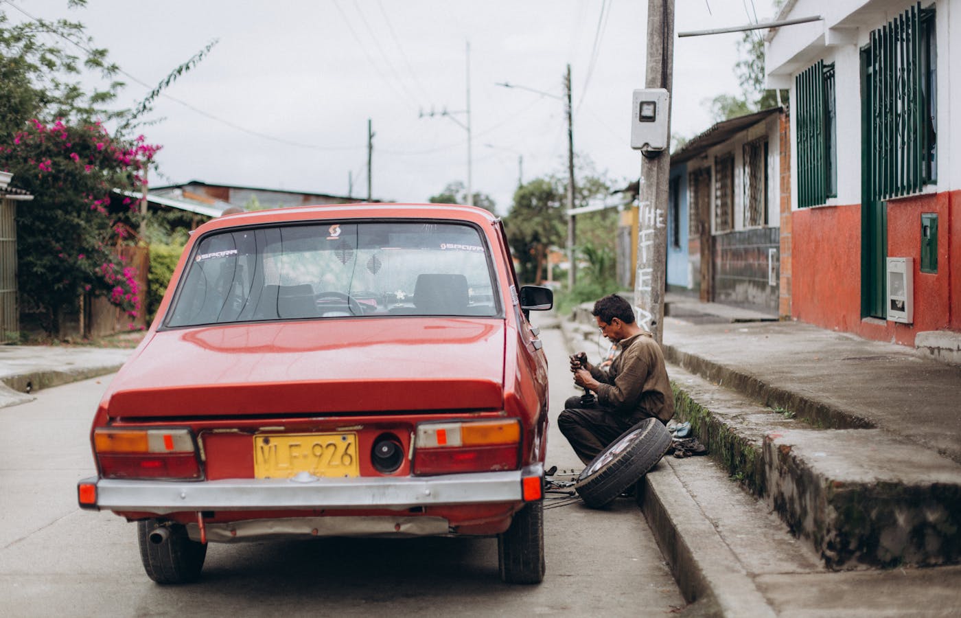 Person working beside a red car with a tire on the roadside
