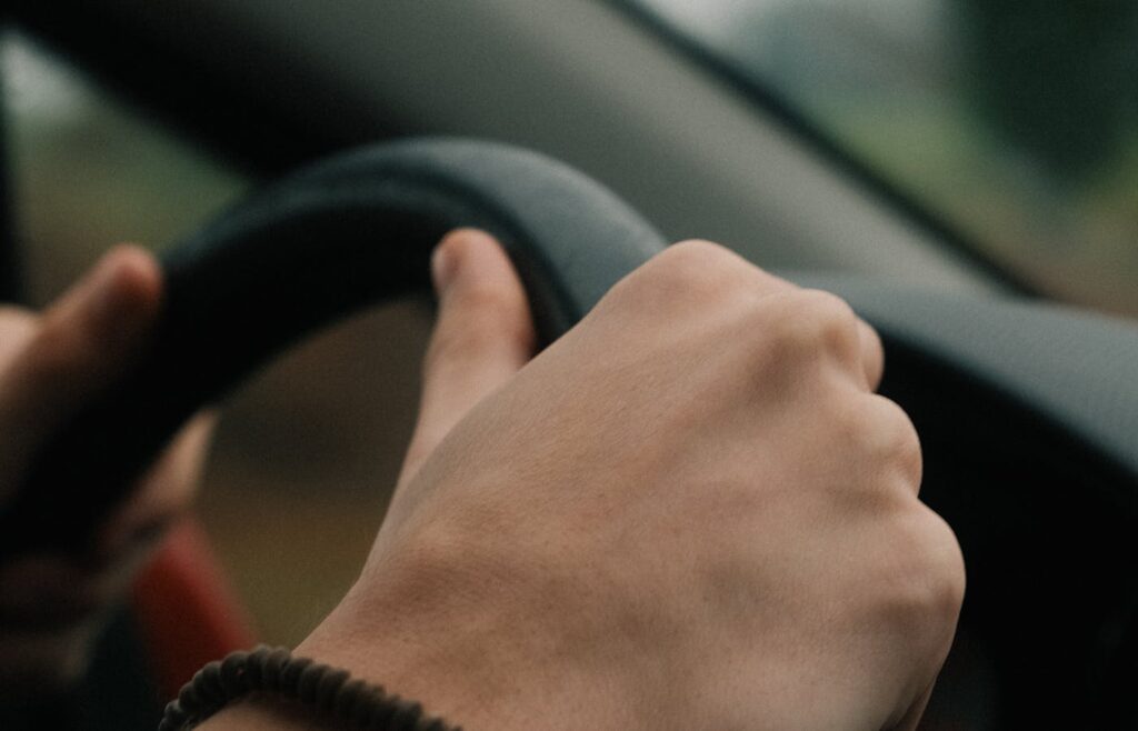 Hand on a steering wheel inside a car