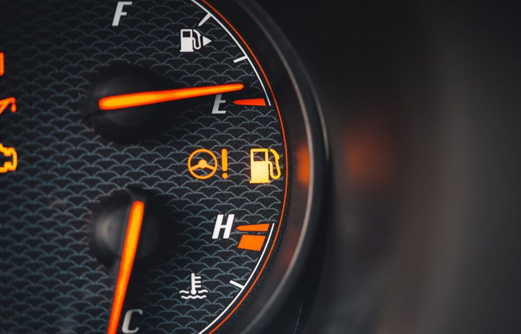 Fuel and steering warning icons illuminated on a car dashboard gauge