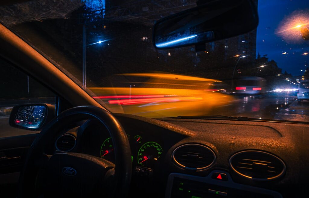 View through a car windshield on a wet city street at night