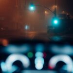 View through a car windshield toward traffic lights on a foggy night street