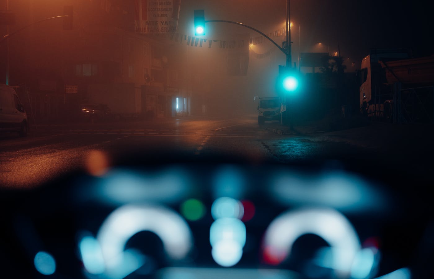 View through a car windshield toward traffic lights on a foggy night street