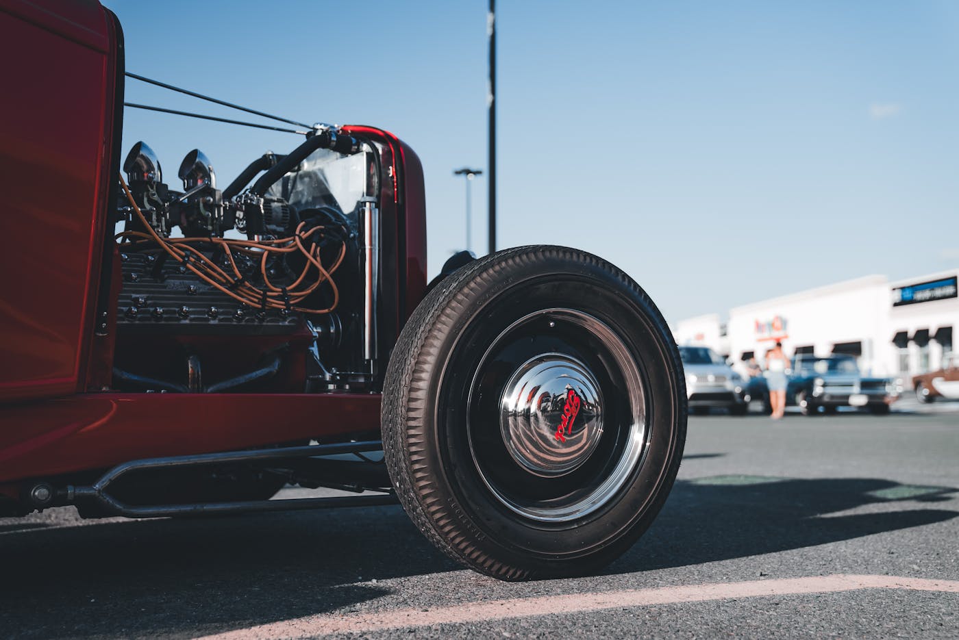 Red classic car with front tire and exposed engine on pavement