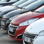 Several cars parked in a row with different colors and front designs
