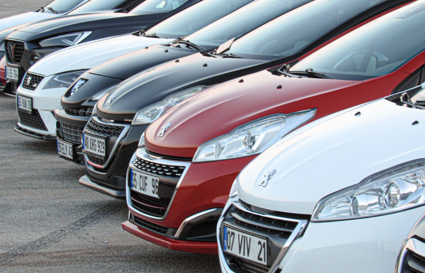 Several cars parked in a row with different colors and front designs