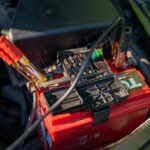 Car battery with jumper cables attached in an engine bay