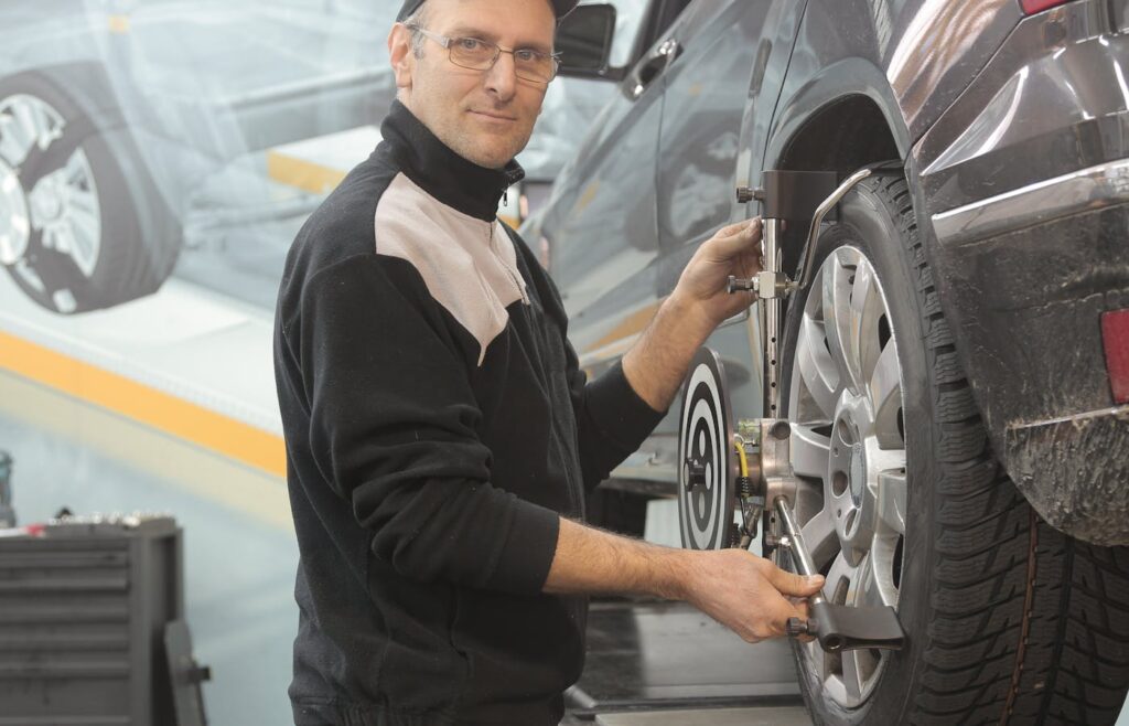 Mechanic using wheel service equipment on a parked car tire
