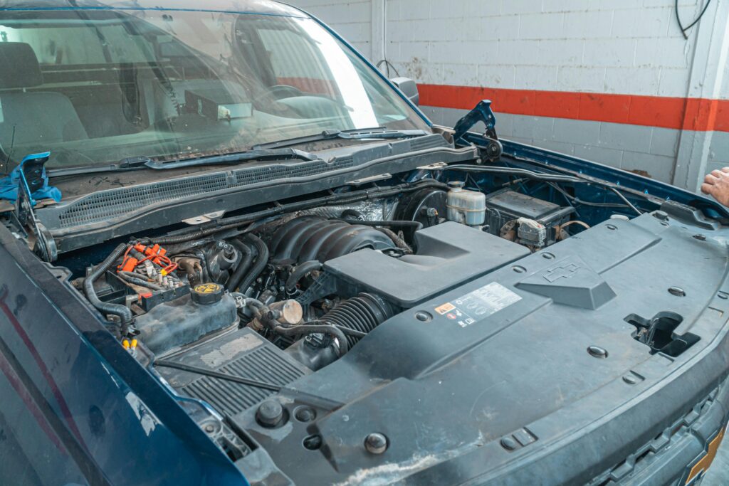 Open car hood showing engine components in a garage