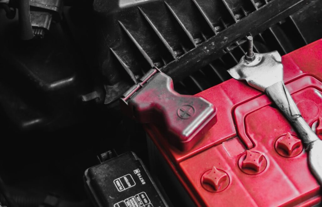 Close-up of a red car battery inside an engine bay