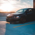 Black car parked on a rooftop lot with the sun low in the sky