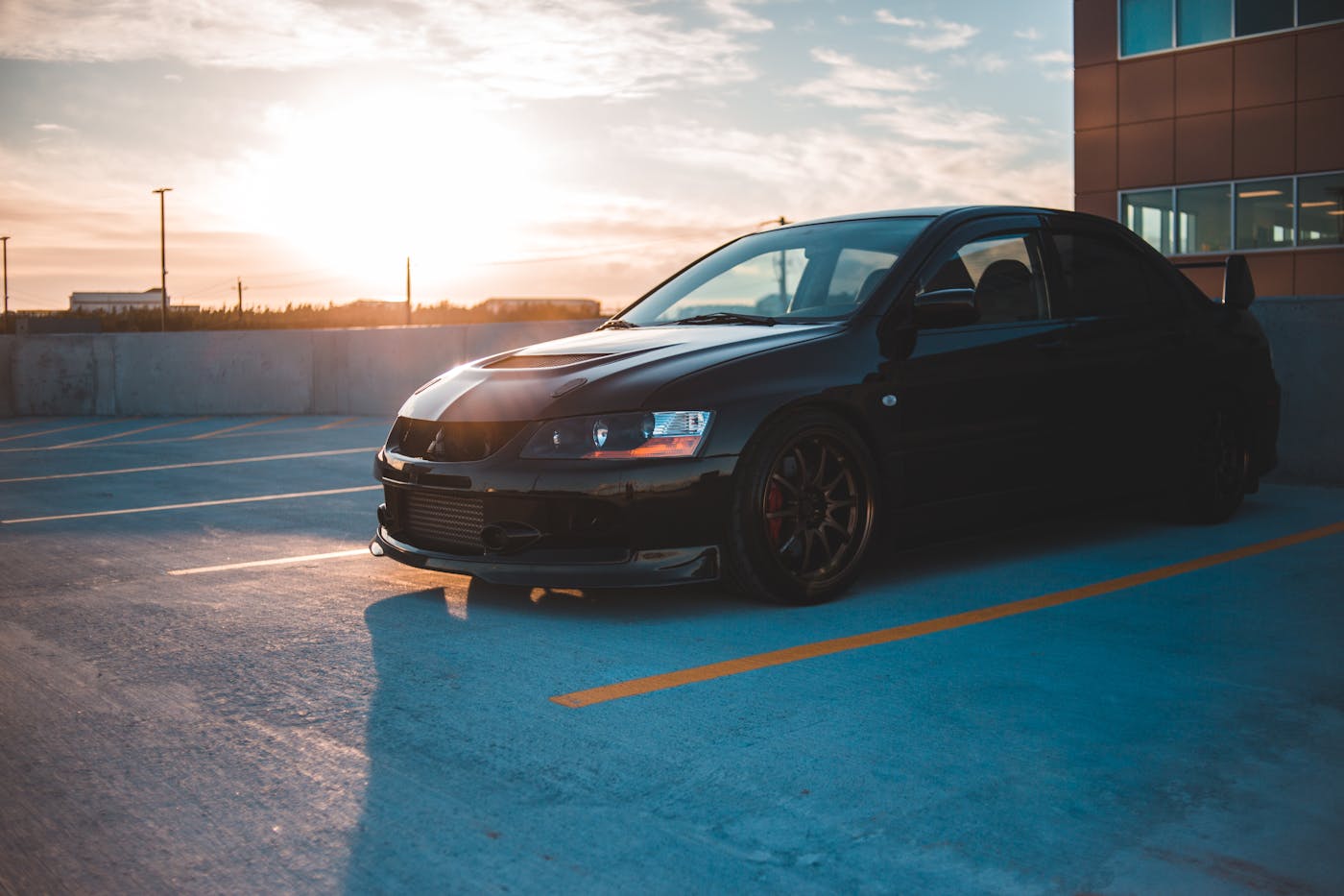 Black car parked on a rooftop lot with the sun low in the sky
