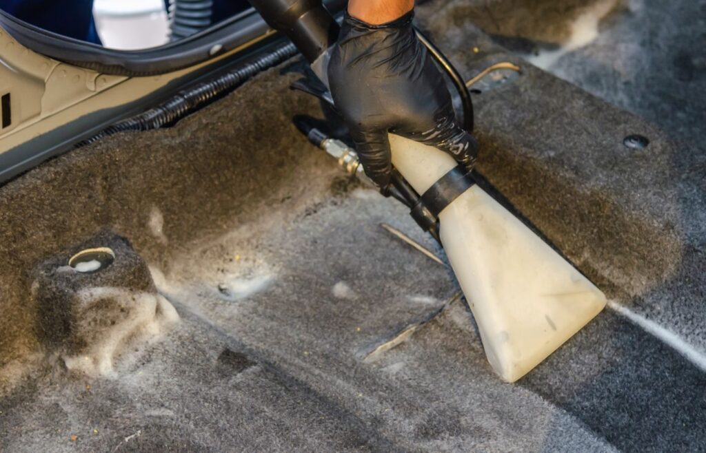 Car interior carpet being cleaned with an extractor nozzle
