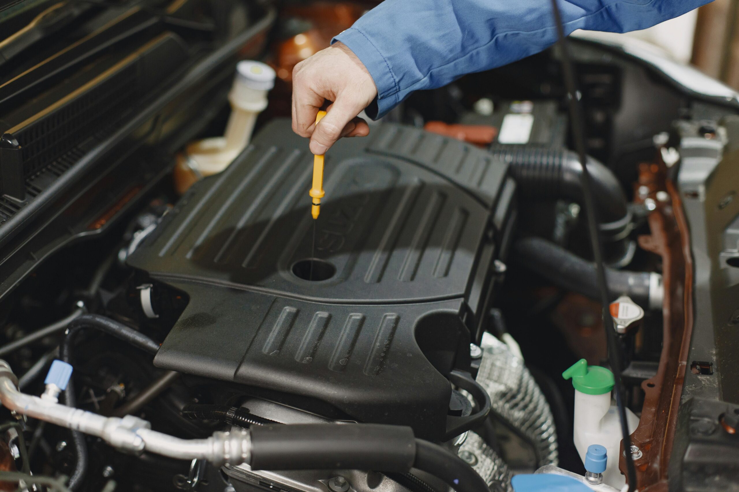 Hand checking car engine oil during maintenance