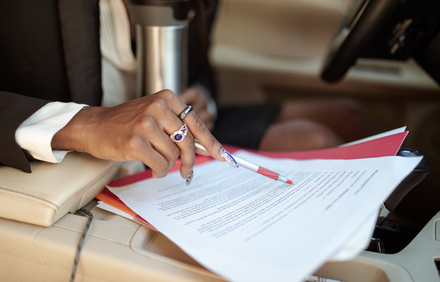 Person holding papers and pen inside a car