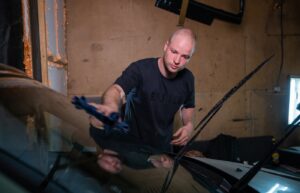 Person wiping a car windshield with a blue cloth