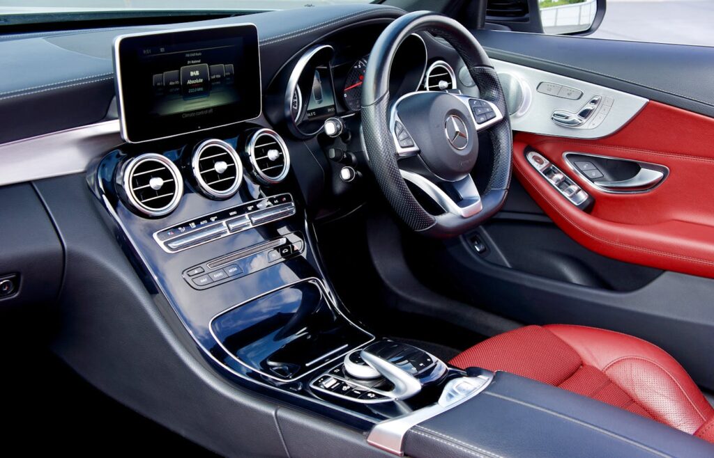 Car interior with steering wheel, screen, controls, and red seats