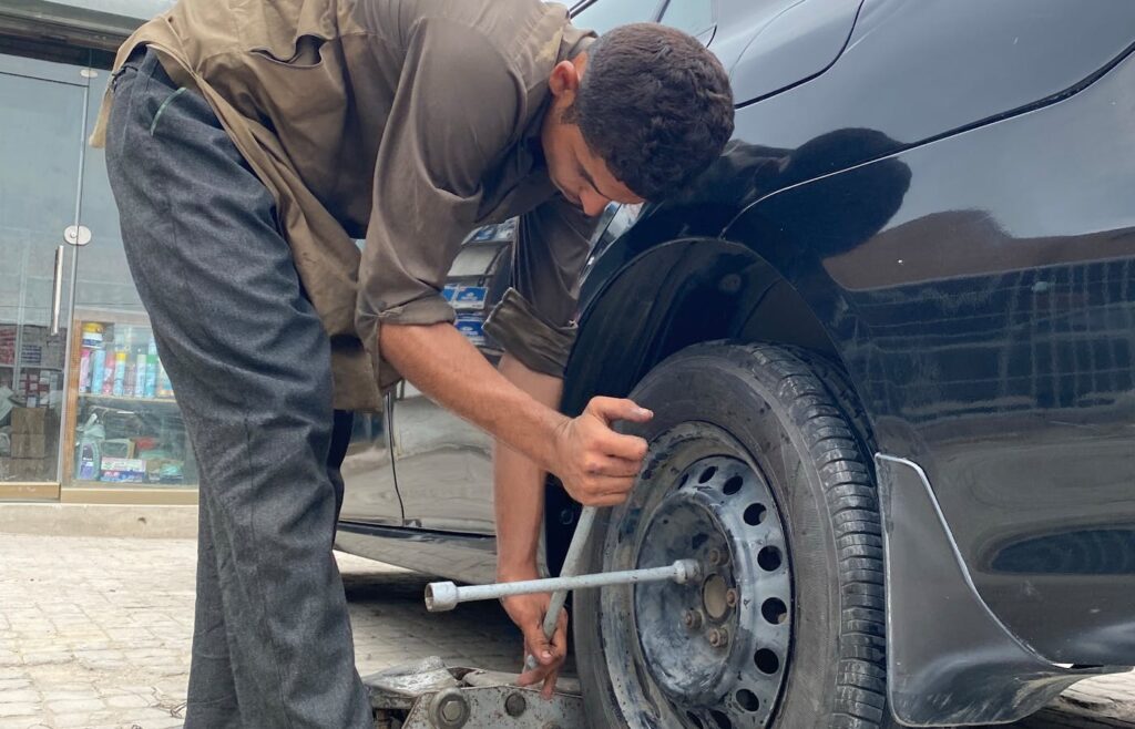 Person using a lug wrench on a black car wheel