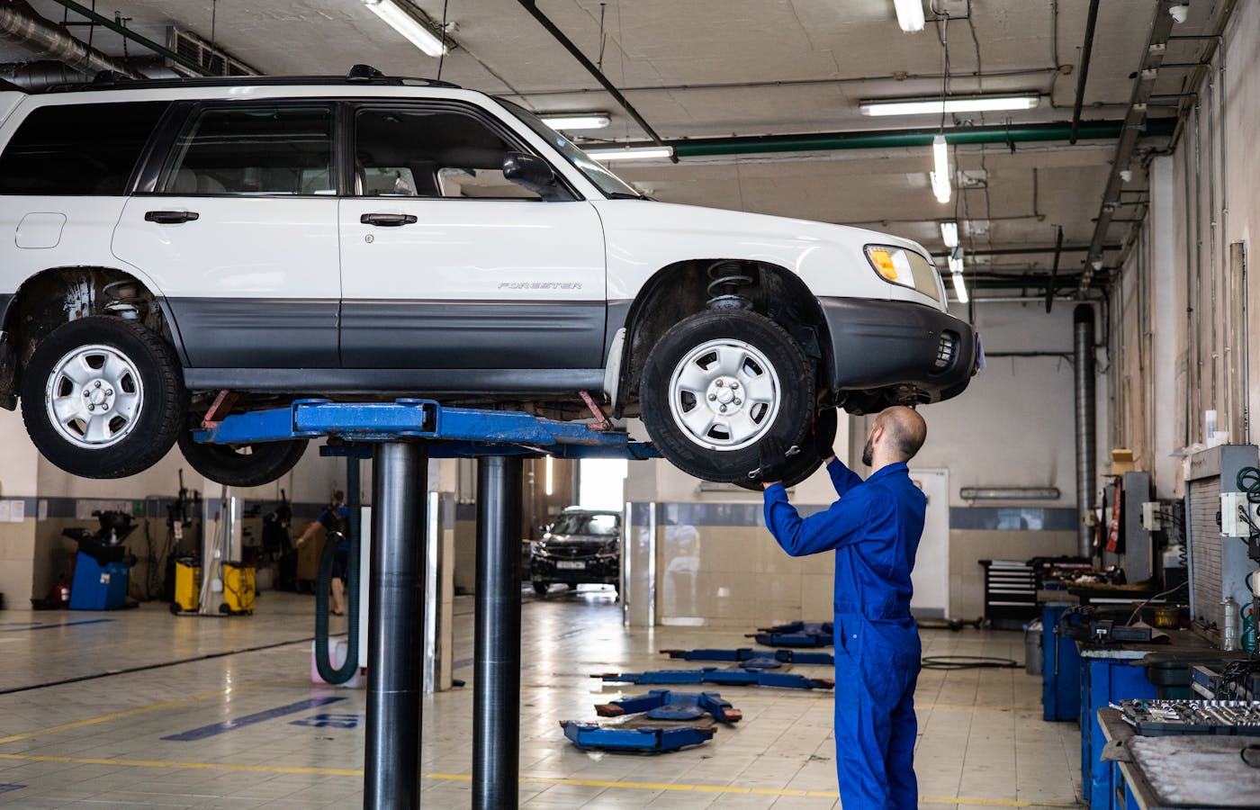 Mechanic inspecting a white car on a lift