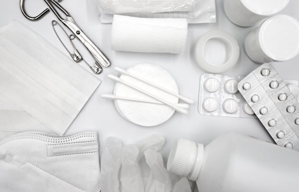 Bandages cotton swabs medical tape and tablets arranged as first aid supplies