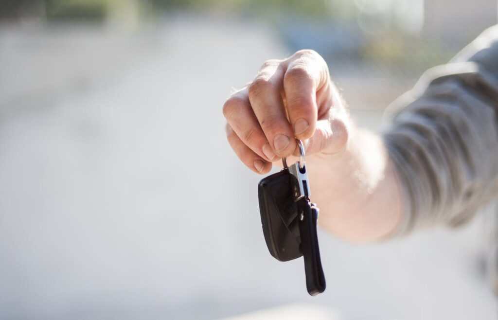 Hand holding a car key for a first-time owner