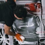 Person washing the rear side of a car with soap