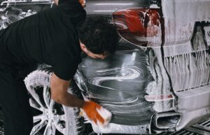 Person washing the rear side of a car with soap