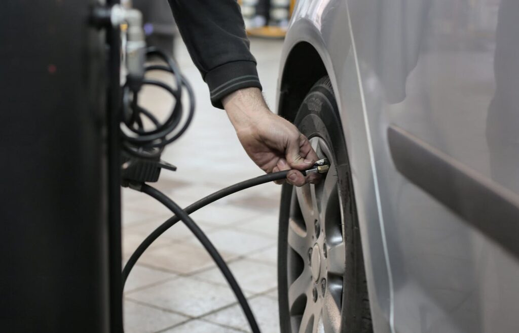 Mechanic checking tire pressure on a car tire in an auto repair shop